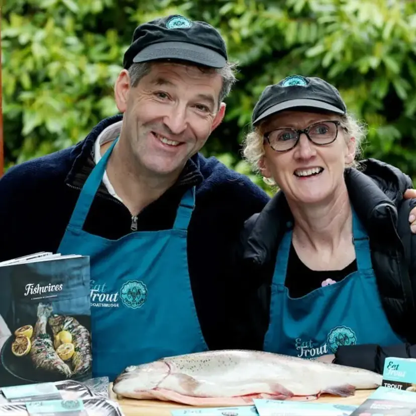 Ger and Mag in behind a table that has fish and cookbook on it