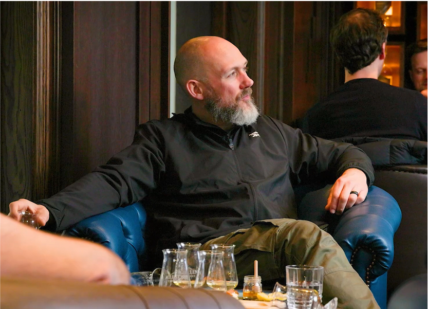 Man sitting in arm chair with whiskey in front of him