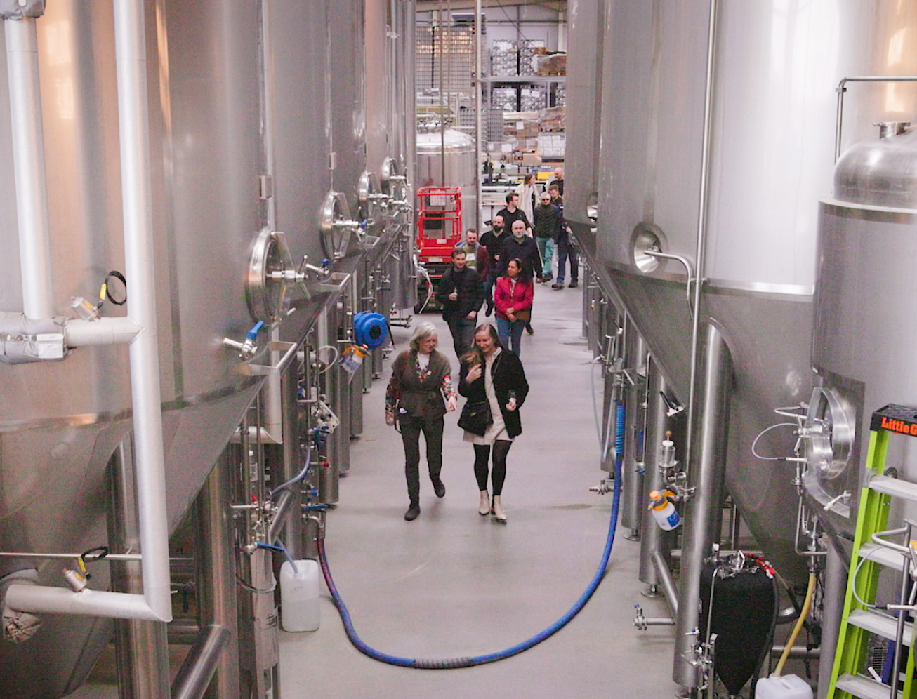Group walking through large brewing facility with large vats