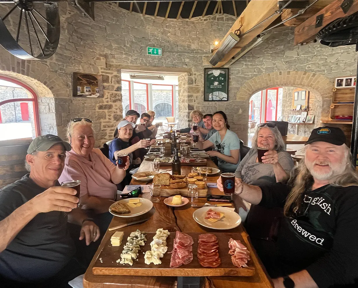 Tour Group Gathered around a large table sampling beer and food