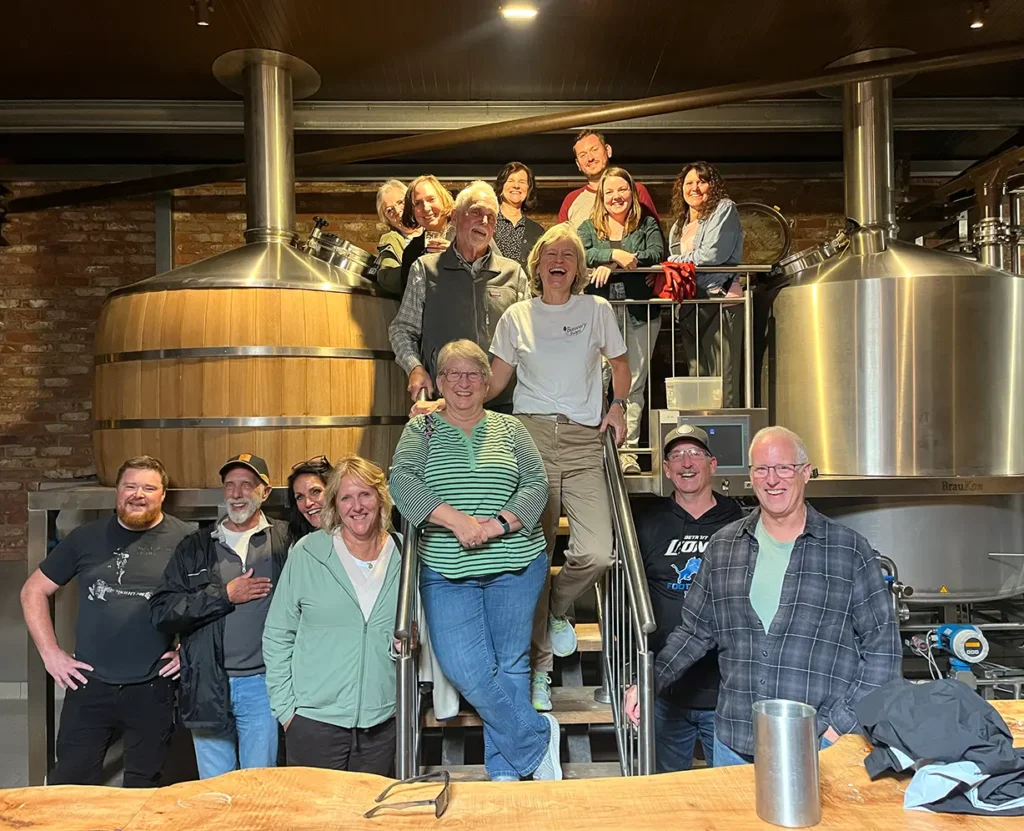 Group tour standing beside brewing equipment